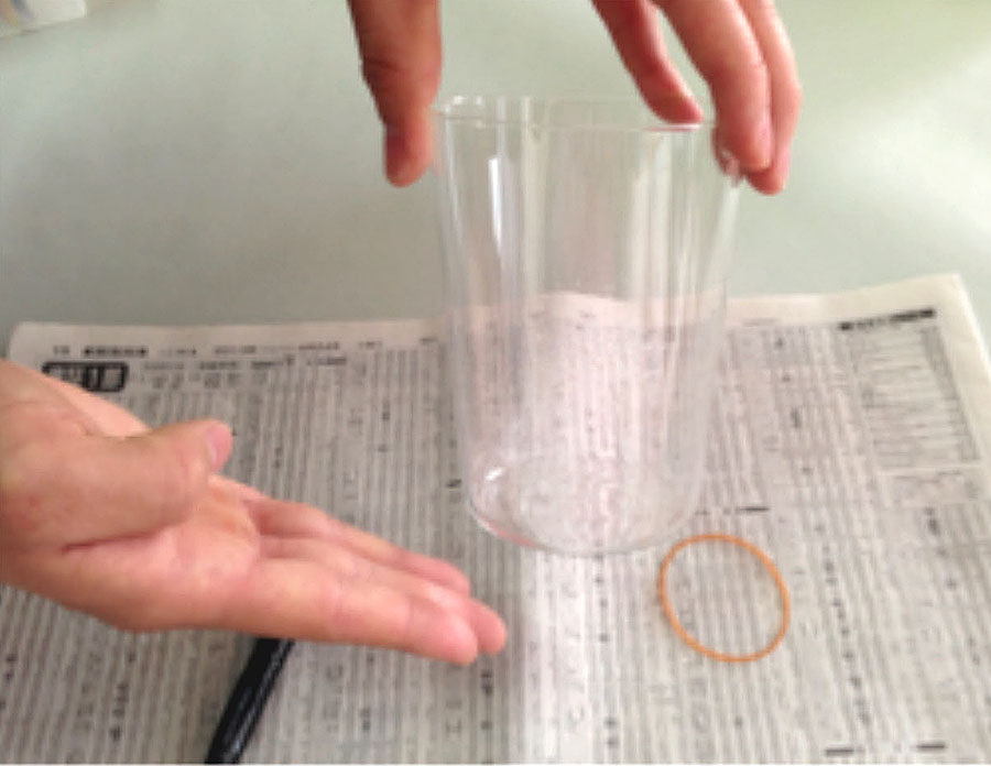 実験操作3: ガラスコップを軽くたたいて，余分なアイシャドウの粉を落とす。