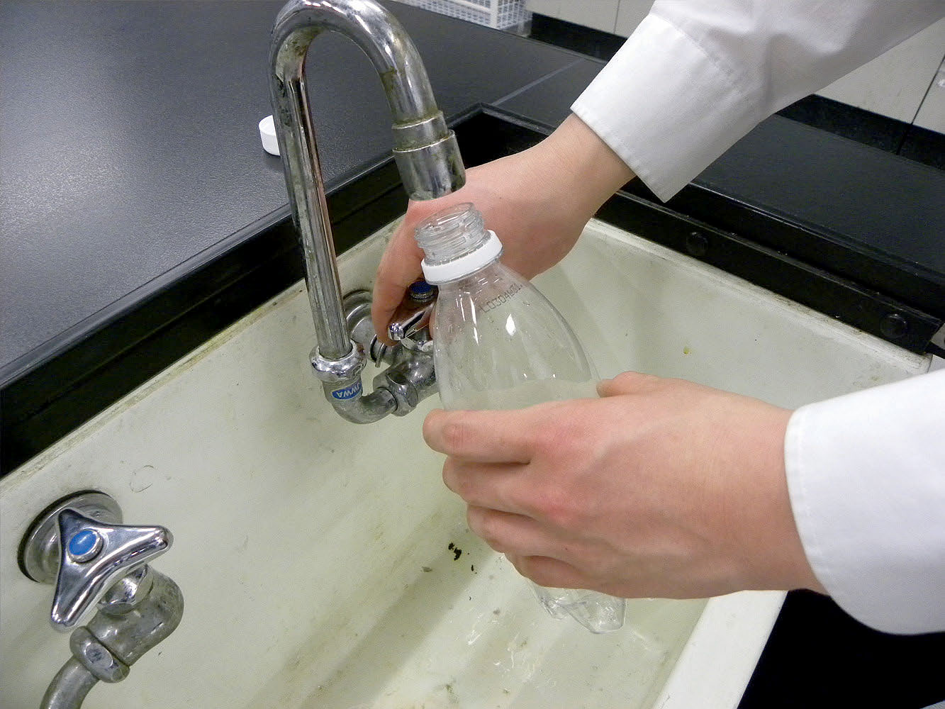 実験操作1: ペットボトルに少量の水を入れ，蓋を閉めてからよく振る。中を十分に濡らしたら，水を流しに捨てる。