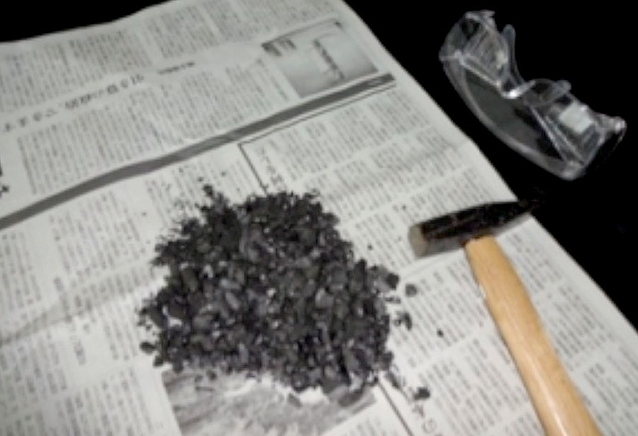 実験操作3: 備長炭を新聞紙にくるみ，金づちで細かく砕き，ペットボトルに詰めやすい大きさにする（厚手のポリエチレン製袋に入れてから，金づちで叩いてもよい）。　注意：保護メガネを必ずかけて，備長炭の破片が目に入らないように　砕いた備長炭を台所用水切りネット袋に入れ，よく水洗いして，細かすぎる備長炭の粒を除く。